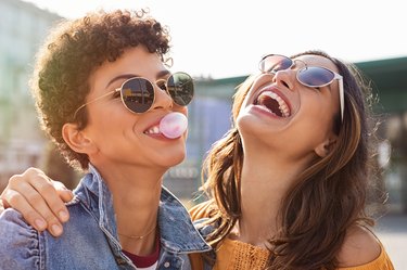 Two women laughing together and chewing gum